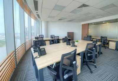 Bright open-plan office with multiple rows of desks, ergonomic chairs, and large windows.