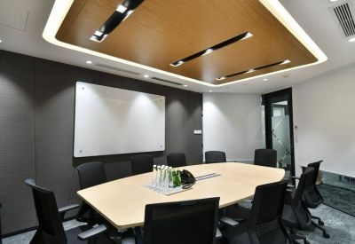 Professional meeting room with a large light wood table, black chairs, and a whiteboard.