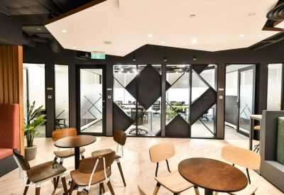 Modern coworking space with geometric ceiling panels, café seating, and glass partitions.