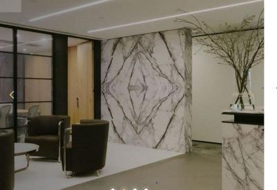 Reception area featuring a dramatic book-matched marble feature wall and dark lounge chairs.