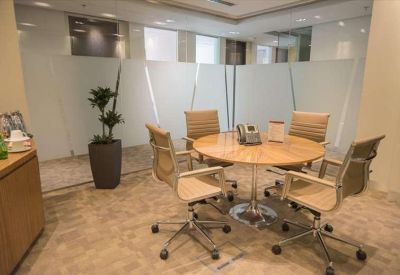 Round meeting table surrounded by four office chairs in a glass-walled room.
