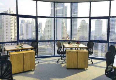 Open-plan office with wooden desks and panoramic city views.