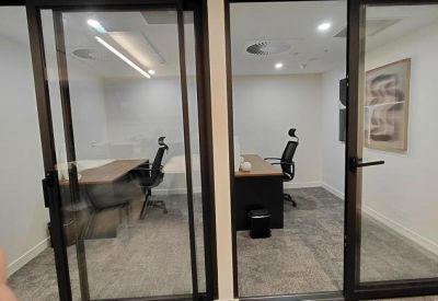 Two private glass-fronted office suites with desks and ergonomic chairs.