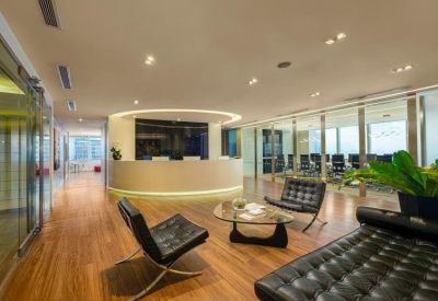 Bright reception area with curved desk, wooden flooring, and modern lounge seating.