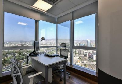 Private corner office with floor-to-ceiling windows offering a panoramic city view and natural light.