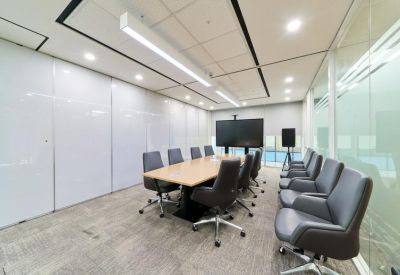 Formal boardroom with a light wood table, grey ergonomic chairs, and white storage wall.