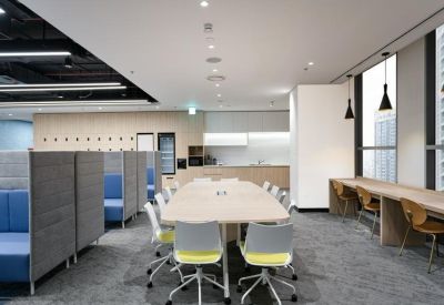 Communal lounge area with a long wooden table, colourful chairs, and private phone booths.