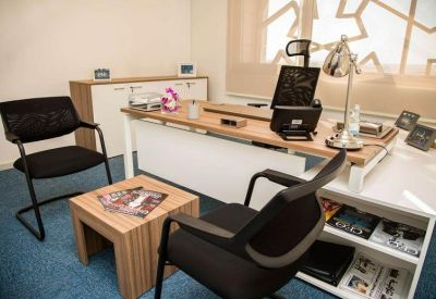 Private office featuring a wooden desk, black chairs, and blue carpeting.