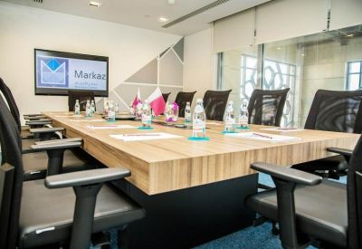 Professional boardroom with a large wooden table and black mesh chairs.