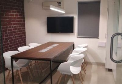 Meeting room with a wooden table, white chairs, and a feature brick wall.