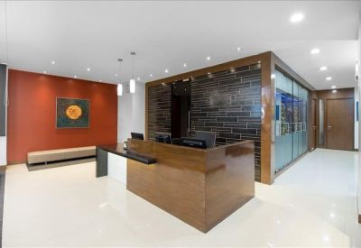 Professional reception area featuring a polished wood desk and burnt orange accent wall.