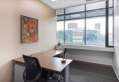 Private corner office with an L-shaped desk and framed wall art.