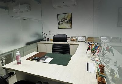 Private executive office with an L-shaped desk, leather chair, and framed certificates on the wall.