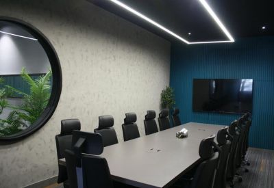 Modern conference room with a large grey table, black ergonomic chairs, and a circular wall portal.