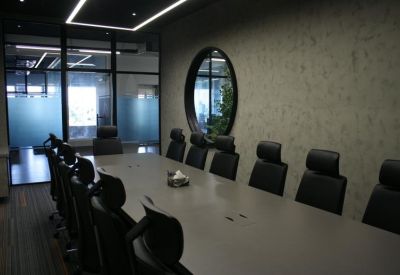 Professional boardroom featuring a long meeting table and dark blue accent wall with a wall-mounted TV.