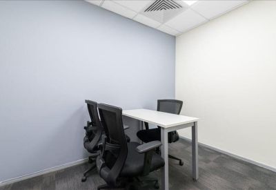 Small meeting room with a white table and three black mesh chairs against a blue feature wall.