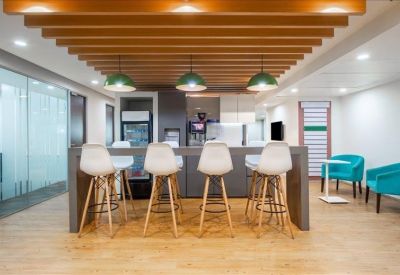 Modern office kitchen and lounge area with a breakfast bar and high-top seating.