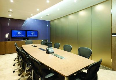 Professional meeting room with a large wooden table and dual monitor screens.