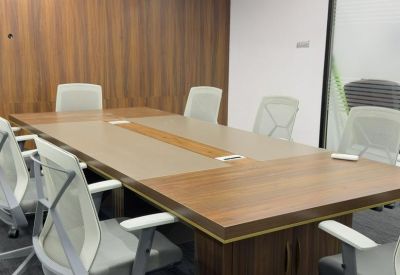 Professional boardroom with a large wood-grain table, mesh chairs, and a feature wood-paneled wall.
