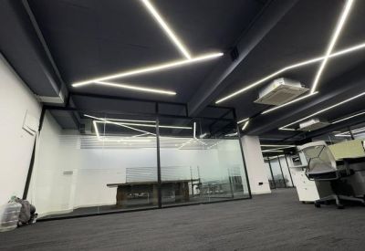 Wide view of a modern office interior featuring geometric LED lighting and glass-walled meeting rooms.