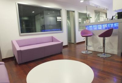 Modern lounge area with a purple sofa, bar stools, and a blue-lit counter.