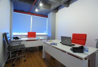 Private office suite featuring two white desks, red ergonomic chairs, and a large window.