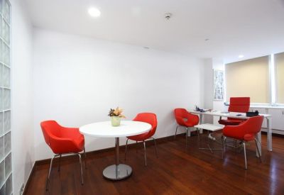 Bright meeting room with a round white table and four vibrant red armchairs.