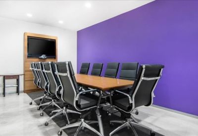 Modern conference room with a large wooden table and a bold purple feature wall.