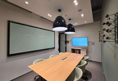 Meeting room with two large screens, a wooden table, and black pendant lights.