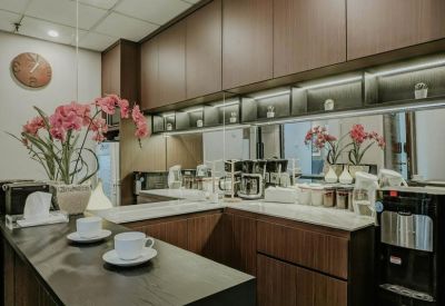 Sleek office kitchen and coffee bar with dark wood cabinetry and pink floral accents.