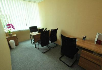 Private office with two workstations, wooden desks, and black ergonomic chairs.