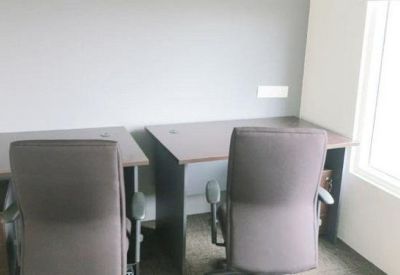 Private office space featuring two dark wood desks and ergonomic chairs beside a large window.