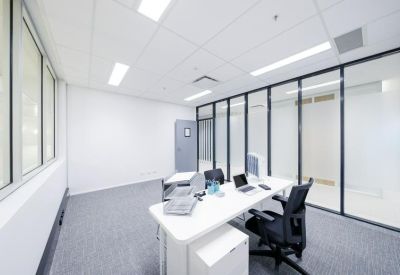 Bright private office suite with a glass wall and minimalist white desk.