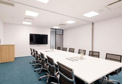 Large professional boardroom with a long white table and teal carpeting.