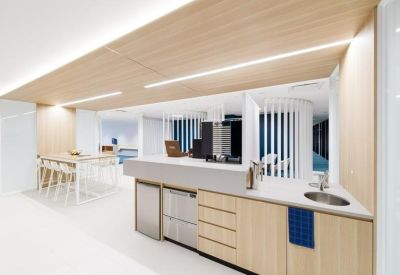 Modern kitchenette with wood cabinetry and an integrated sink.