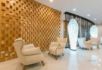 Bright reception lounge with modern wingback chairs and a decorative geometric wood wall.