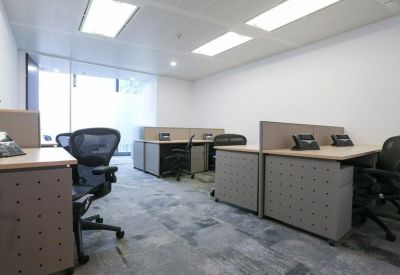 Open-plan office space with grey workstations and ergonomic mesh chairs.