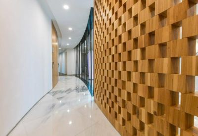 Brightly lit marble hallway flanked by a glass wall and a textured wooden partition.