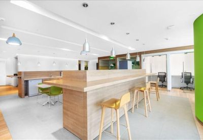 Communal breakout area featuring a long wooden bar counter and stylish stools.