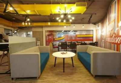 Modern breakout space with grey and blue sofas arranged around a circular white coffee table.