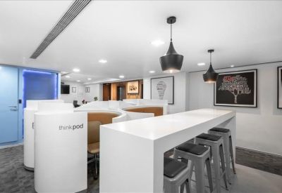 Communal breakout area with high-top seating and sleek white counters.