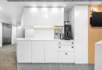 Modern kitchen and communal breakout area with white cabinetry and coffee station.