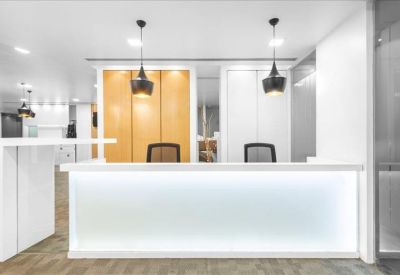 Bright, minimalist reception desk with hanging pendant lights and warm wood paneling.
