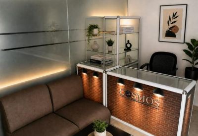 Reception area with a brick-patterned desk, brown leather sofa, and glass display shelving.