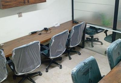 Shared workspace with a long wooden desk and mesh office chairs.
