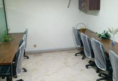 Coworking space featuring long wooden desks, task lighting, and indoor greenery.