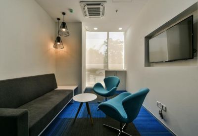 A modern lounge area at N Heights with blue swan chairs and a large wall-mounted screen.
