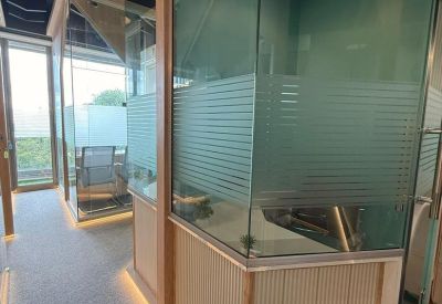 Modern glass-walled private office pods with wood accents and ambient floor lighting.