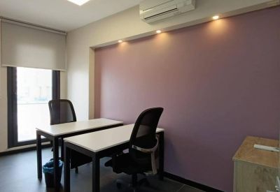 Private office with two white desks and black mesh chairs against a purple feature wall.