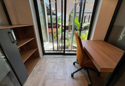 Private office workstation with a wooden desk and glass doors opening to a terrace.